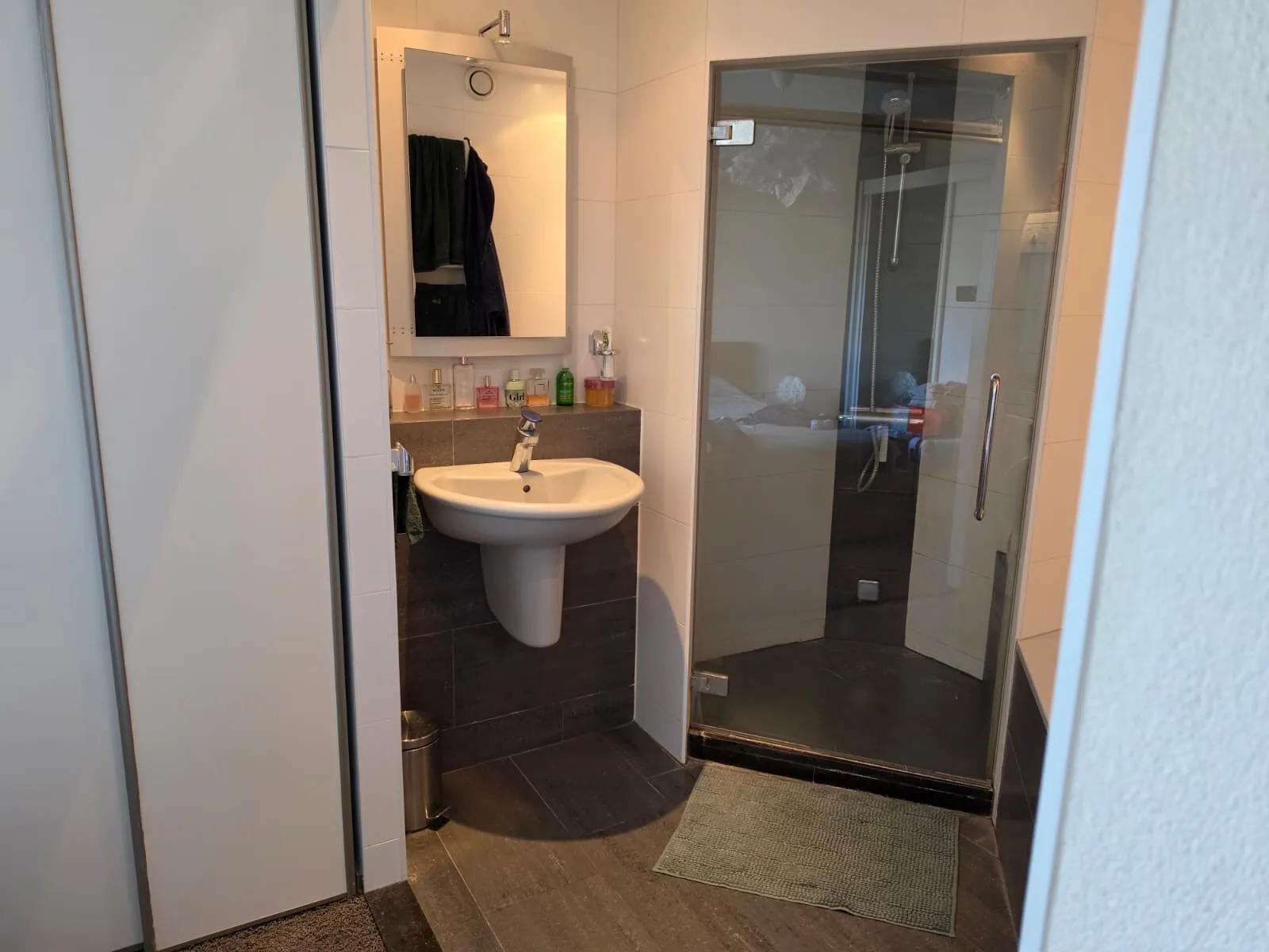 Moderne badkamer met douche, wastafel en spiegel.