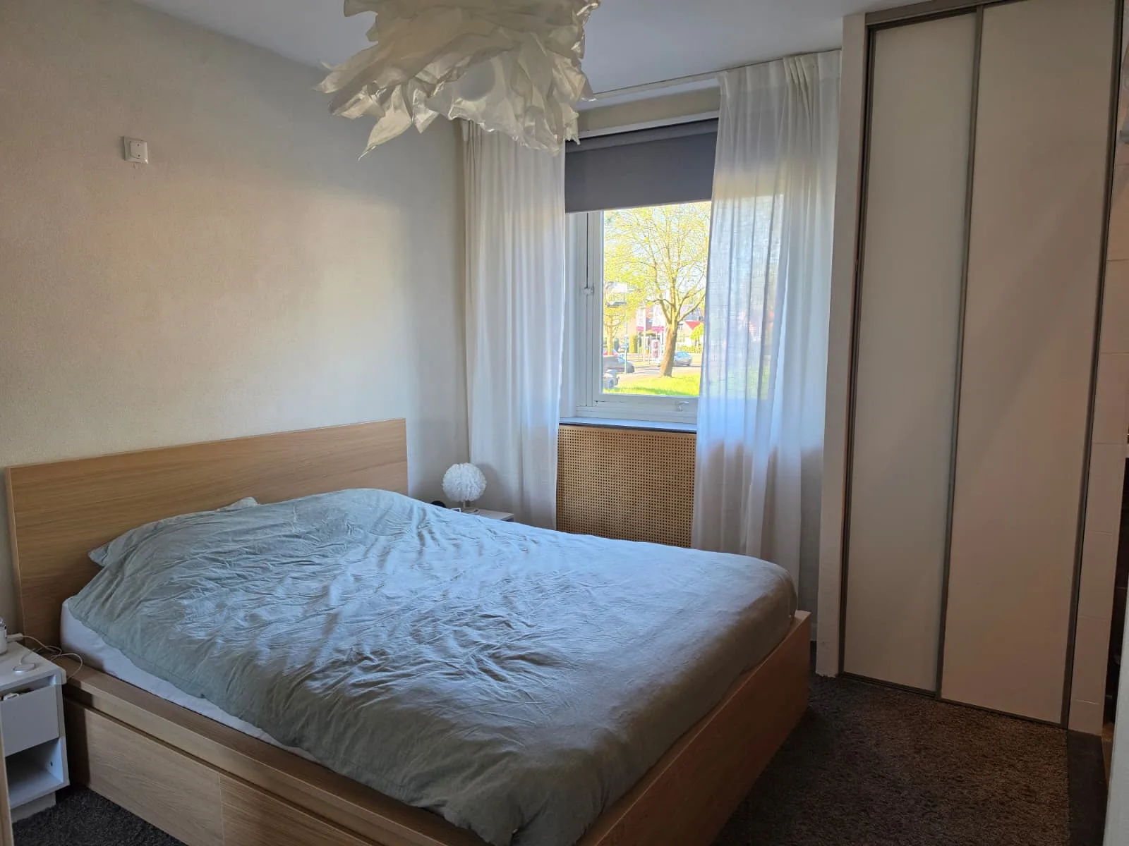 Slaapkamer met bed en raam met gordijnen in appartement.