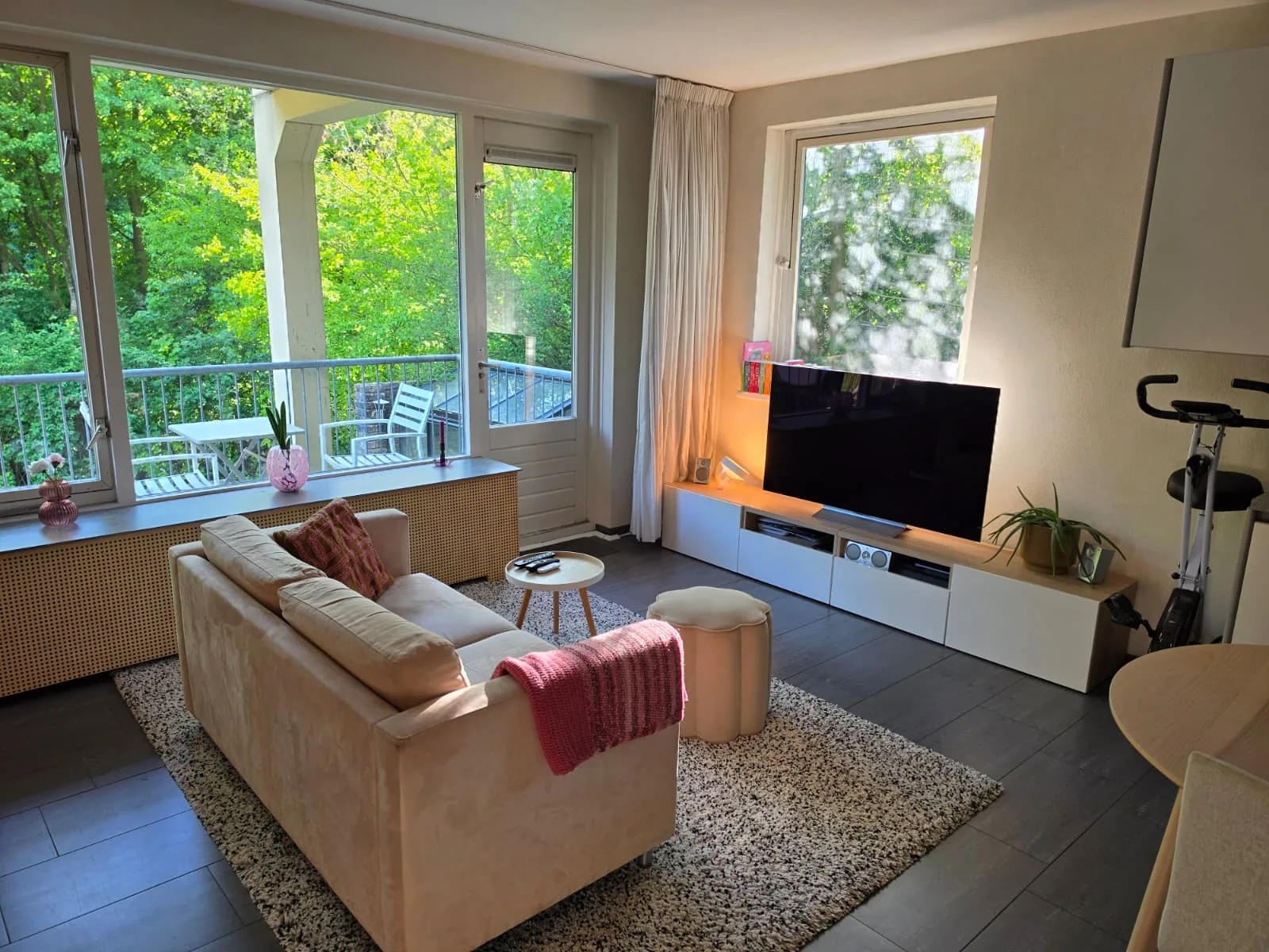 Moderne woonkamer met bank, tv en toegang tot balkon.
