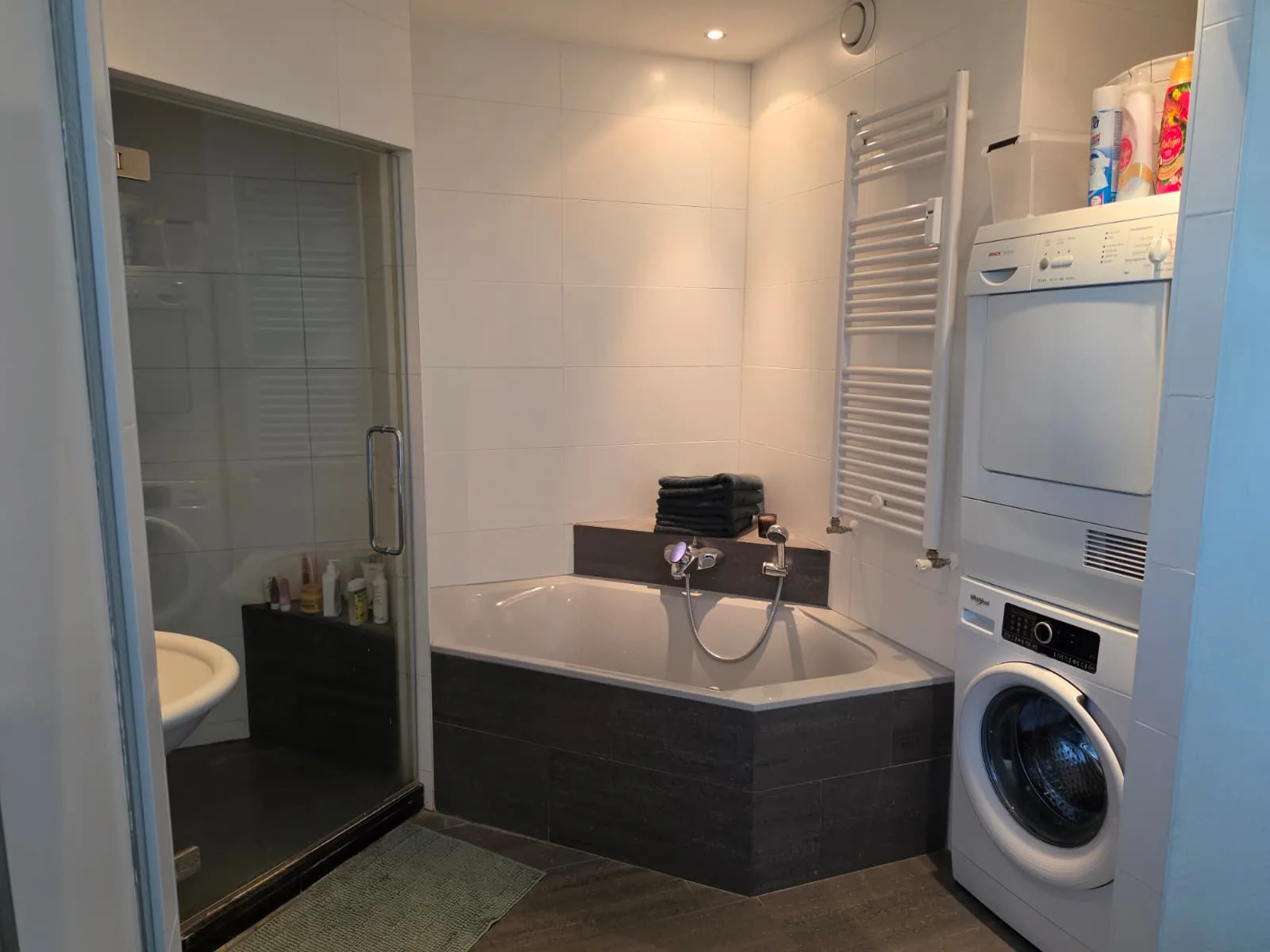 Moderne badkamer met ligbad, douche en wasmachine.