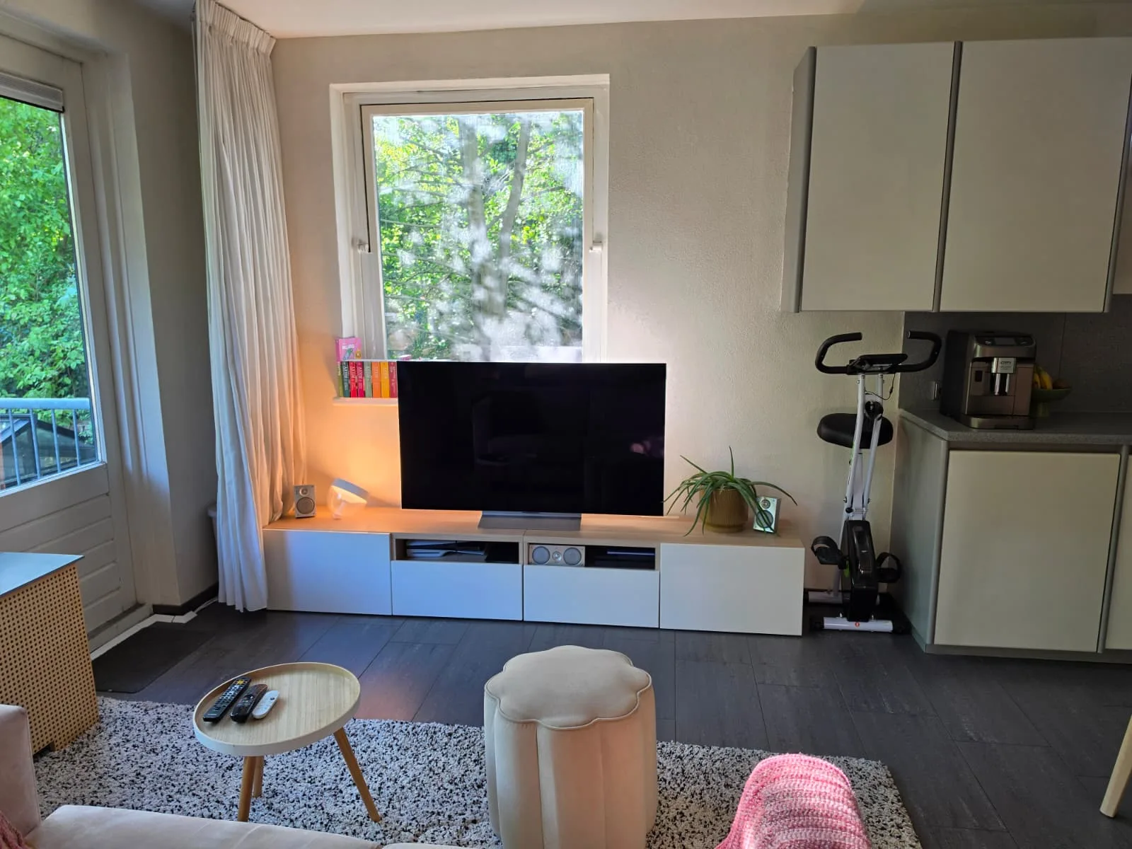 Woonkamer met televisie, kast en keuken in appartement.